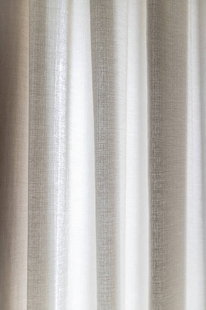 istock Soft wavy curtain fabric in neutral beige and white tones lit by natural daylight. The image highlights interior comfort, modern decor, and the gentle flow of light through textured textiles. 2244330662