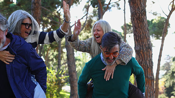 istock Senior friends having fun piggyback riding in park 2244343708