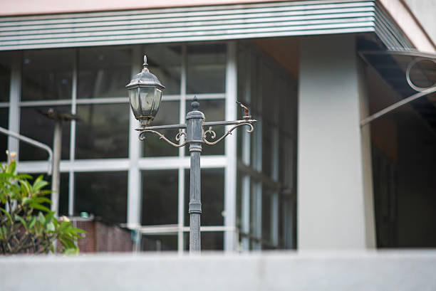 A charming vintage street lamp stands tall against the backdrop of a modern building, blending old-world charm with contemporary architecture in an urban setting.