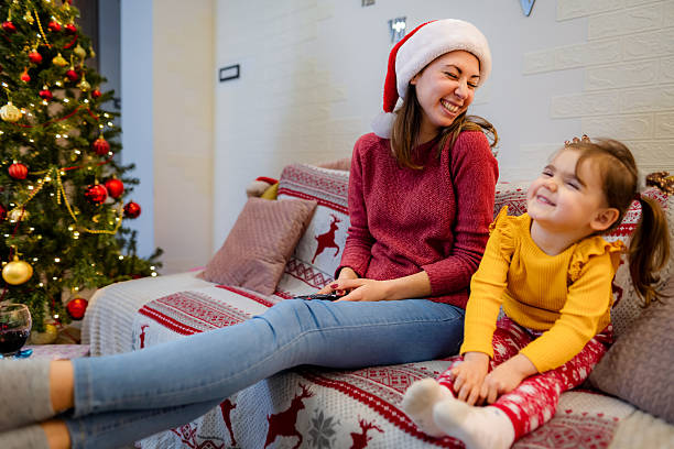 istock Mother and daughter laughing on Christmas couch 2244350037