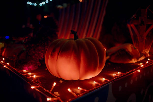 Decorative pumpkin surrounded by string lights with red and orange LEDs, creating a warm, festive, and mysterious atmosphere at night.