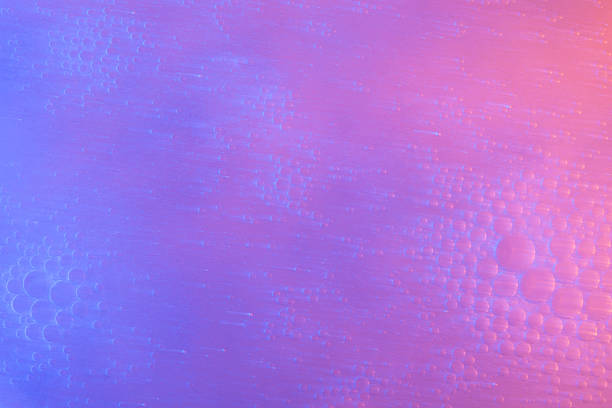 Macro abstract background of oil and water creating bubbles, illuminated by vibrant neon purple and pink/orange gradient lighting with long light streaks.