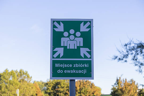 istock Green emergency evacuation assembly point sign, clearly visible outdoors, featuring people and arrows symbol, indicating a public safety and crisis management location 2244354145
