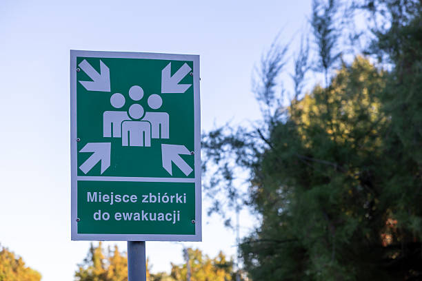 istock Green emergency assembly point sign with white people icon and arrows indicating a safe gathering area for public safety during an evacuation 2244354150