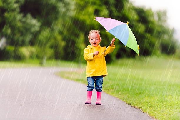 istock Happy funny child with multicolored umbrella under the summer raining day 2244354664