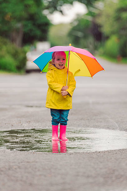 istock Happy funny child with multicolored umbrella under the summer raining day 2244354691