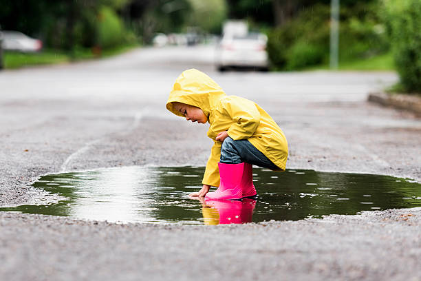 istock Happy funny child with raincoat under the summer raining day 2244354713