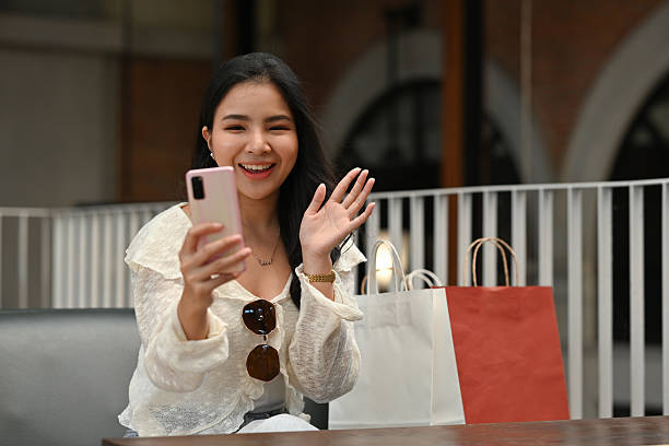 istock A Stylish Asian woman using her phone for a video call, sharing her shopping experience while sitting outside a boutique store 2244357538