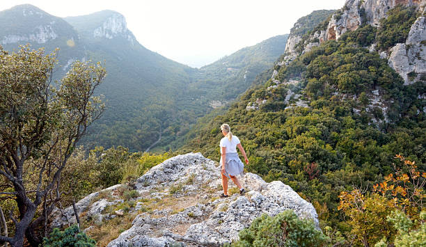 Senior woman hikes rugged hilltop above valley, maritime alps, Finale LIgure, Liguria