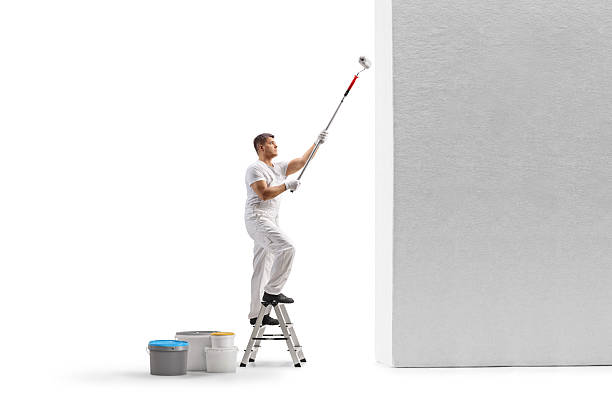 istock Painter on a ladder painting a wall with a roller 2244359026