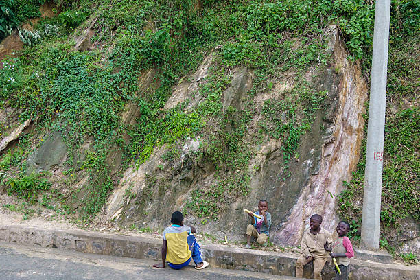 Nyungwe Rwanda - September 6 2025; Group four boys sittingon edge of highway happily chewing on sugarcane sticks.