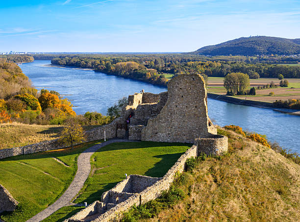 Devin, Slovakia - October 19, 2025: Scenic view of ancient Devin castle ruins by a Danube river with autumn foliage.