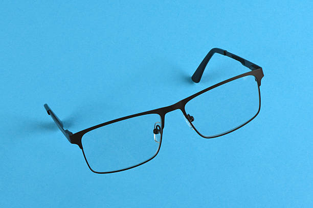 Reading glasses isolated on blue background. Glasses hang in air. High resolution photo. Full depth of field.