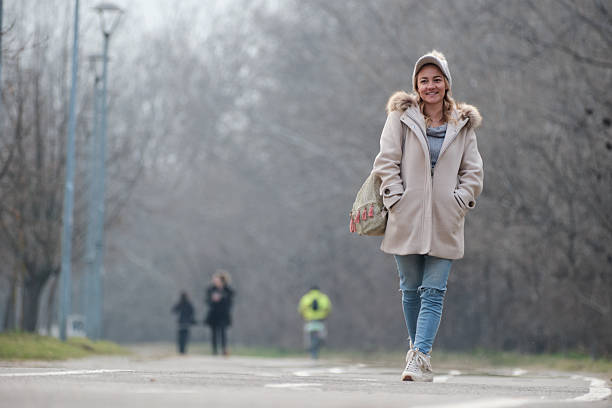 Young woman enjoying a casual walk through a misty park on a cold day.