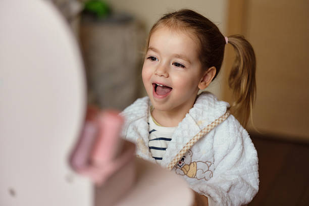 Young child laughing and expressing joy in a white bathrobe with teddy bear embroidery.