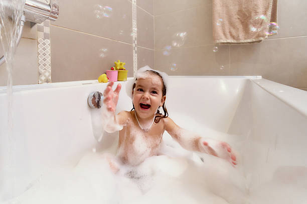 istock Happy little girl enjoying bubble bath playing with foam. 2244368722