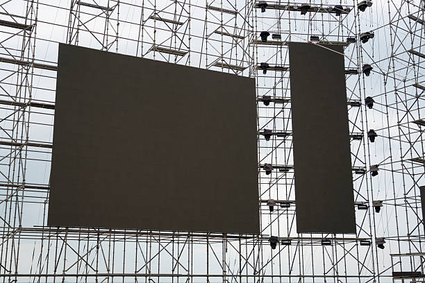 istock A massive stage is being constructed with scaffolding, featuring large blank screens ready for visuals. The activity occurs in an outdoor setting under a cloudy sky in daytime 2244368895