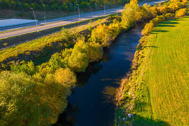 River flowing through autumn landscape with highway and vibrant green field
