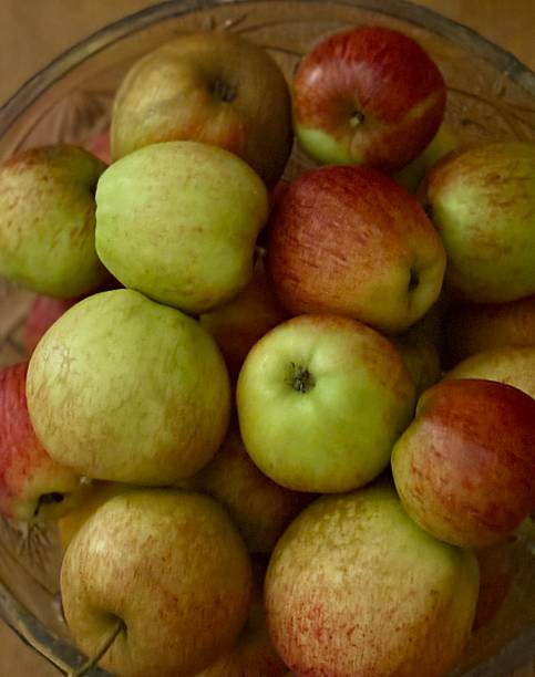 istock A glass bowl overflows with shiny green and red apples, their smooth skins reflecting soft light. Fresh, crisp, and inviting, the apples create a colorful display of natural beauty and harvest charm. 2244379665