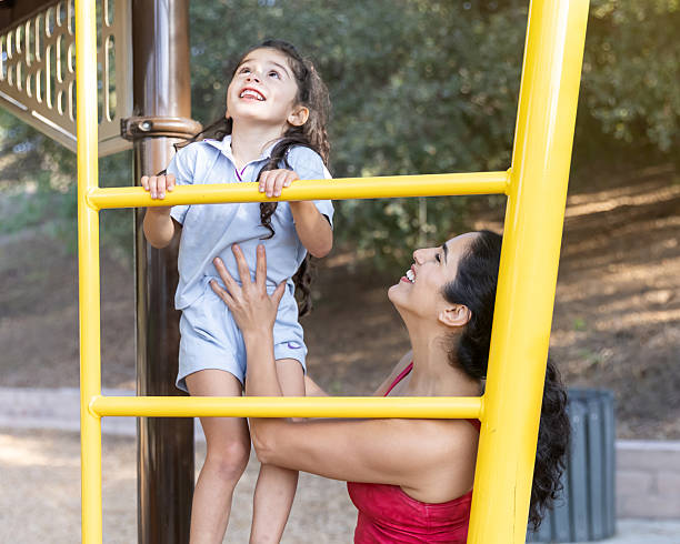 istock Mother helping daughter climb on a play structure 2244383129