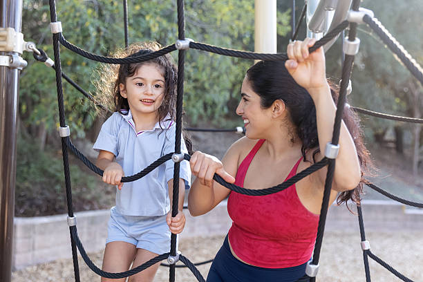 istock Mother helping daughter climb on a play structure 2244383135