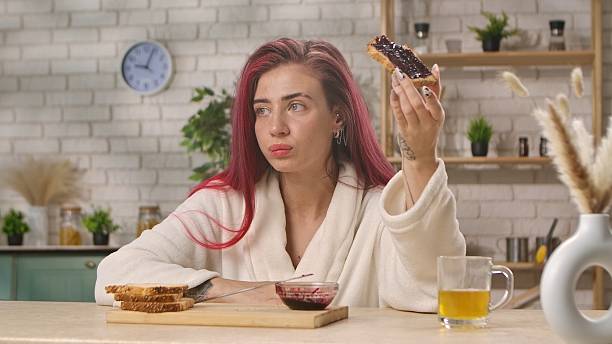 istock Woman in Kitchen Holding Jam Toast and Looking Thoughtful 2244384302
