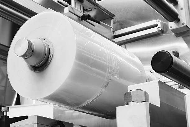 istock Automatic polyethylene plastic bag production machine with lighting effect. Close-up of the roller of the plastic bag production machine in the light blue scene. product packaging concept 2244385875
