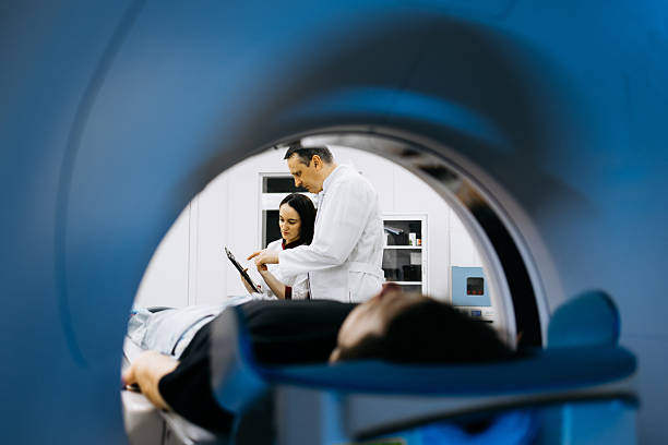 istock Medical professional reviews CT scan images while patient rests on examination table within advanced CT scanner 2244386769