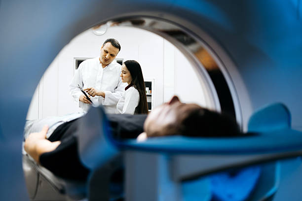 istock Medical professional reviews CT scan images while patient rests on examination table within advanced CT scanner 2244386786