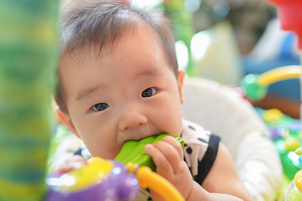 istock A baby is chewing on a green toy 2244391624
