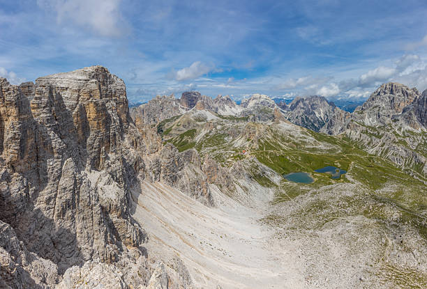 High resolution widescreen panorama of mountain landscape. Panorama of Alps mountains on a sunny day.  Blue sky with some clouds above beautiful summits alpine range Dolomite Alps