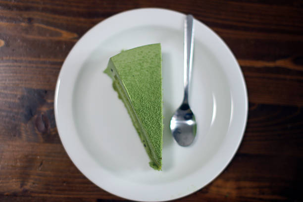 A single slice of green tea cake placed on a white plate beside a spoon, showcasing the vibrant green color.