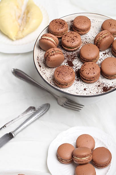 Chocolate macarons are neatly placed on plates, showing their rich and tempting appearance.