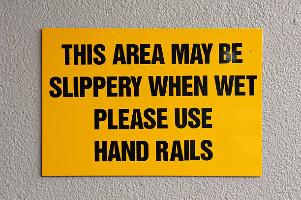 istock Slippery When Wet - Please Use Hand Rails bright yellow warning sign attached to a wall 2244413079