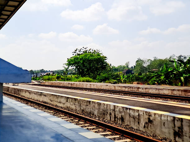 istock A tranquil day at a rural train station platform with greenery and a cloudy blue sky view. 2244418007