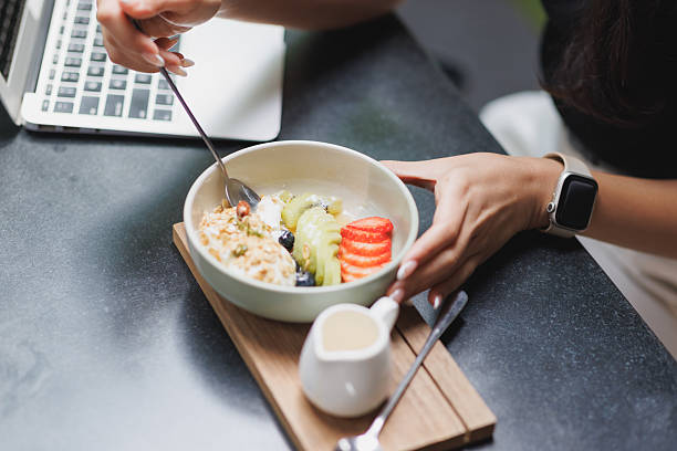 istock Woman eating healthy breakfast while using laptop in cafe 2244419140
