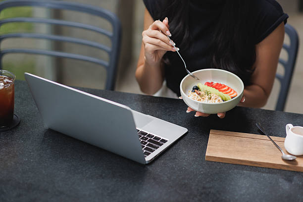 istock Woman multitasking while eating healthy breakfast at cafe 2244419560