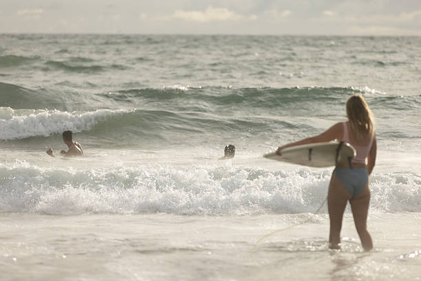 26 January 2025, Canggu Beach - Bali.A young surfer woman walks along Canggu Beach in Bali carrying her surfboard, embodying the area’s vibrant surf culture and relaxed coastal spirit.