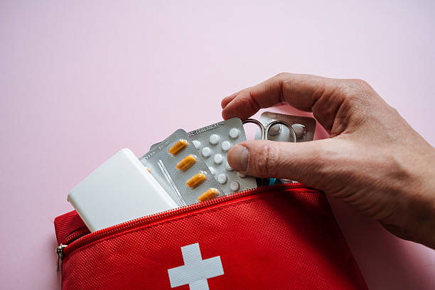 istock A hand is reaching for medication from a bright red first aid kit that is set against a soft pink background, indicating the importance of health and safety in care 2244425578