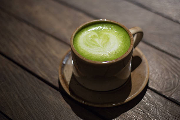 istock Green matcha latte tea with foam art in ceramic cup on wooden table. 2244428826