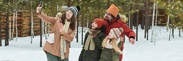 istock Family Taking Selfie Outdoors during Winter Vacation in Snowy Forest 2244433596