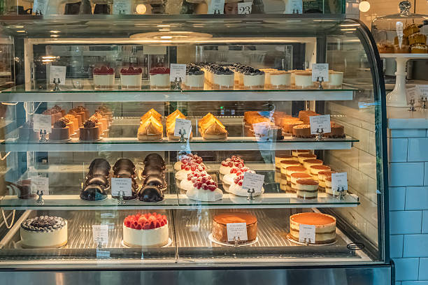 istock Assorted cheesecakes, tiramisu, and chocolate pastries are arranged on multiple shelves inside a bakery display case. 2244434056