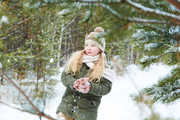 istock Girl Playing with Snow in Winter Forest Surrounded by Pine Trees 2244436364