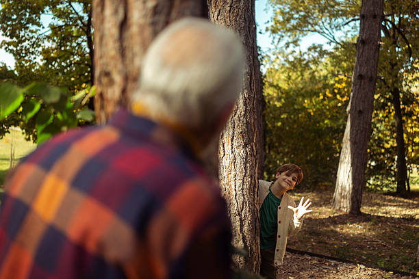 istock A young boy hides behind a tree trunk, waving at his grandfather with a mischievous smile 2244436534