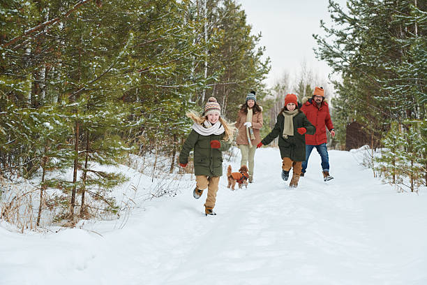 istock Family with Children Running with Dog through Snowy Forest Path 2244436719