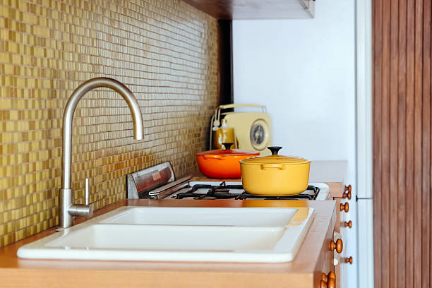 Kitchen countertop with utensils, pans on induction hob, bowls, cutting boards, vegetables