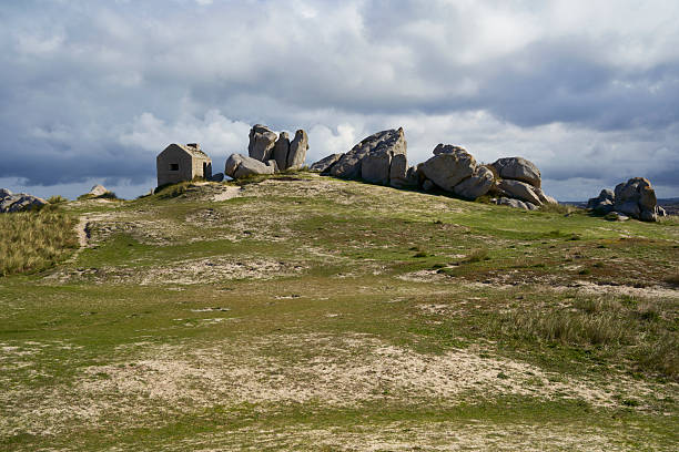 istock An old watchtower stands on a grassy hill, surrounded by large rocks under a cloudy sky, highlighting the historical charm of Brittany. Plage des Amiets, France. 2244438896
