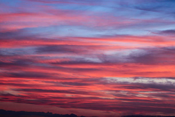 Dramatic cloudy sky displaying a beautiful natural phenomenon with vivid colors from the sun setting, offering a peaceful and awe-inspiring natural backdrop