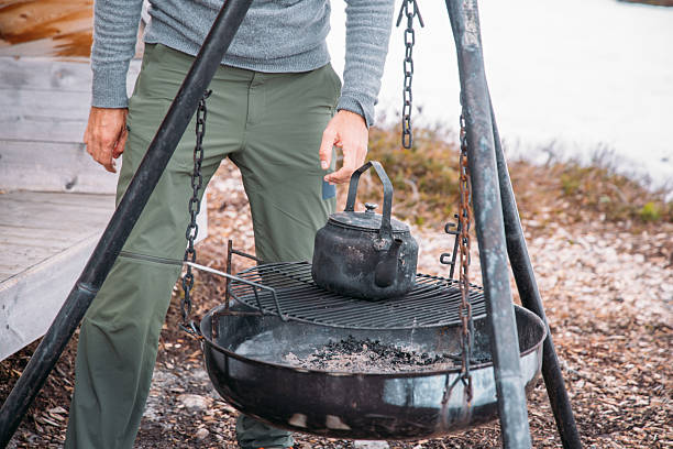 Man Preparing Campfire Kettle Near Shelter in Snow