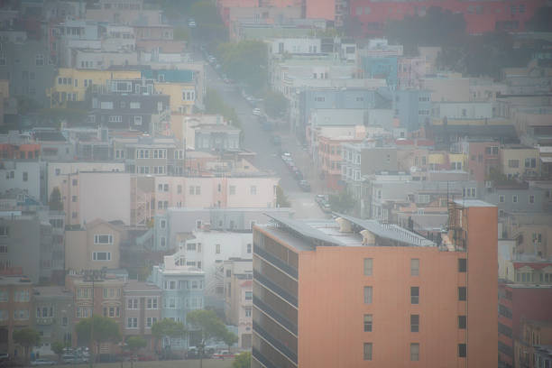 Skyline of SF partially covered in long-hanging clouds.